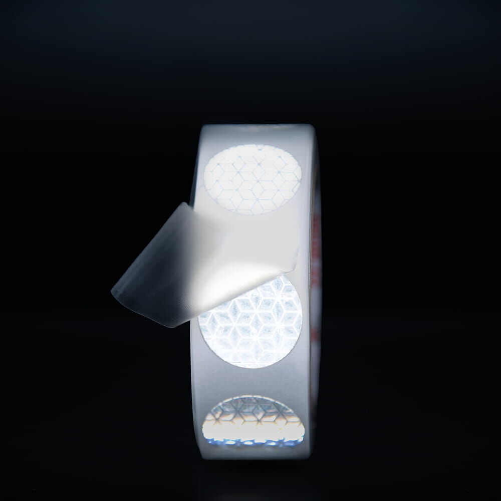 Reflexpunkte leuchten bei Lichteinfall, Applikationstape leicht abgehoben, dunkler Hintergrund