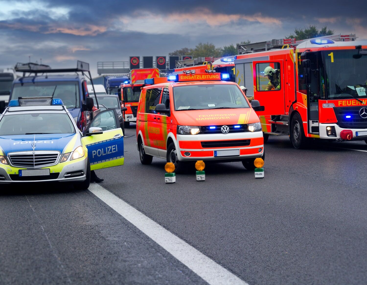 Markierungen speziell für Einsatzfahrzeuge Einsatzfahrzeuge von Polizei, Feuerwehr und Rettungsdienst auf einer Autobahn mit dramatischem Himmel.