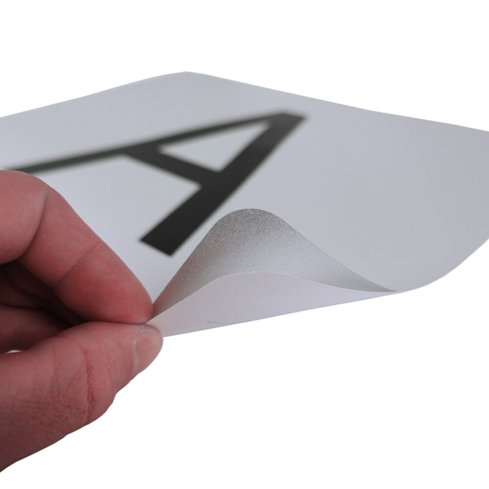 Hand löst flexiblen, wiederablösbaren A-Aufkleber von der Trägerfläche ab