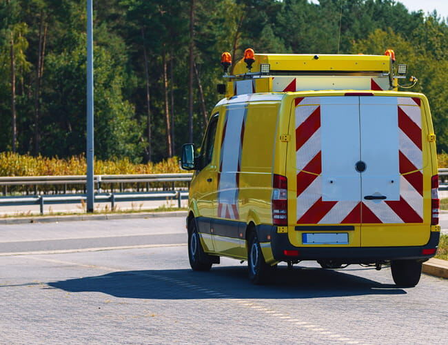 Heckansicht eines gelben Begleitfahrzeugs mit rot-weißer Heckwarnmarkierung