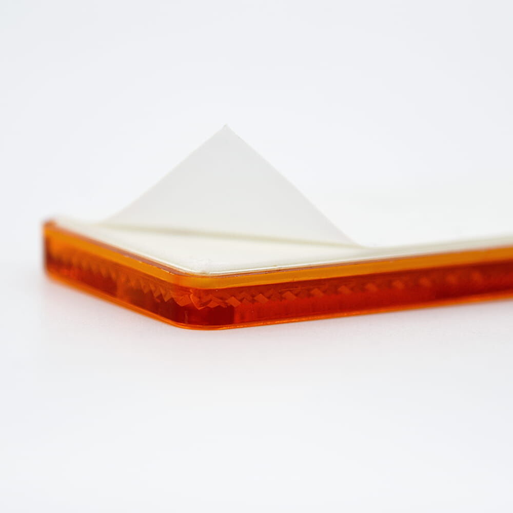 Detail: selbstklebender oranger Reflektor 90×40 mm, Folie abgezogen