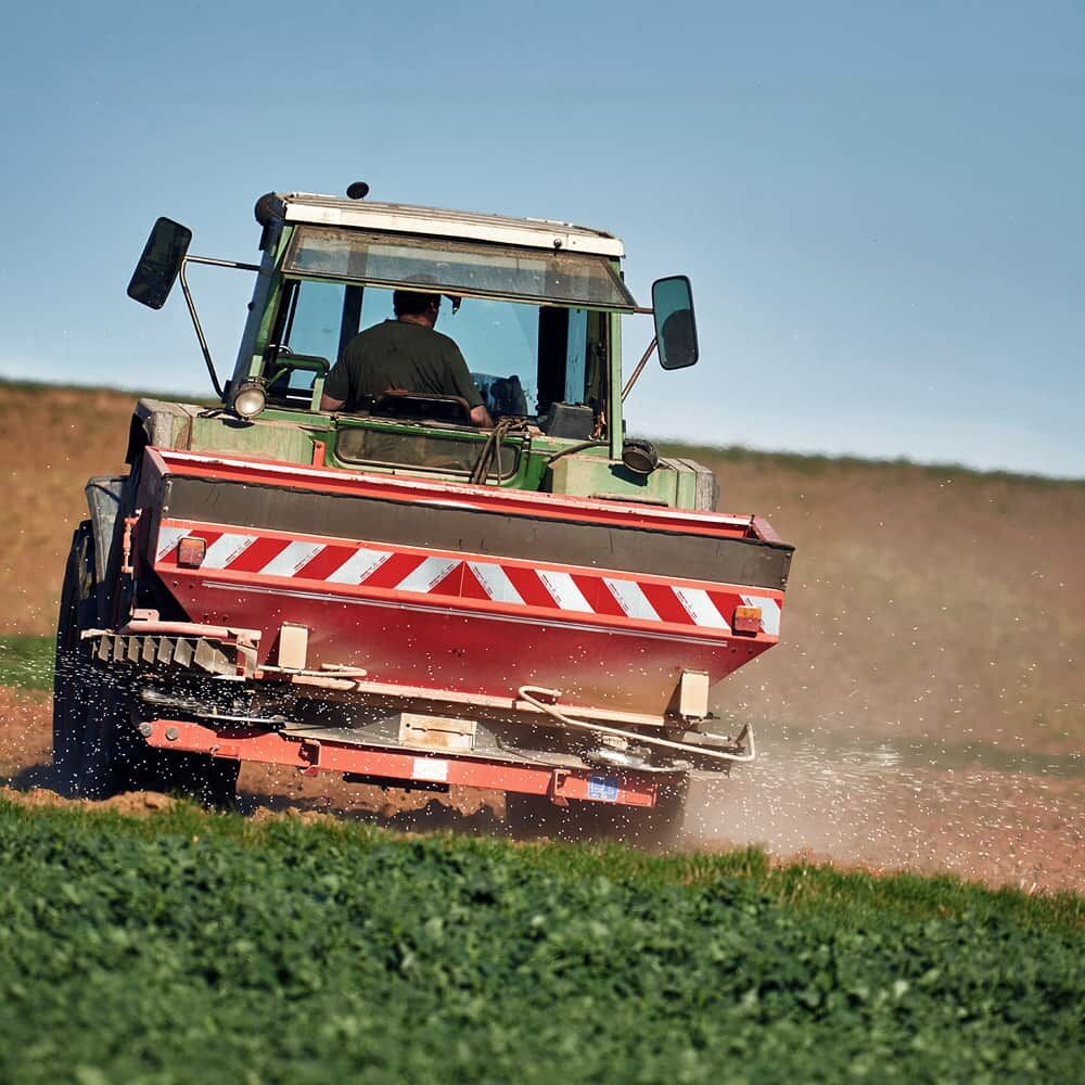 Traktor mit Heckstreuer, ausgerüstet mit 5921M Warnmarkierung rot/weiß im Feldeinsatz