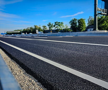 Neue Fahrbahn mit frischen weißen Markierungen unter blauem Himmel.