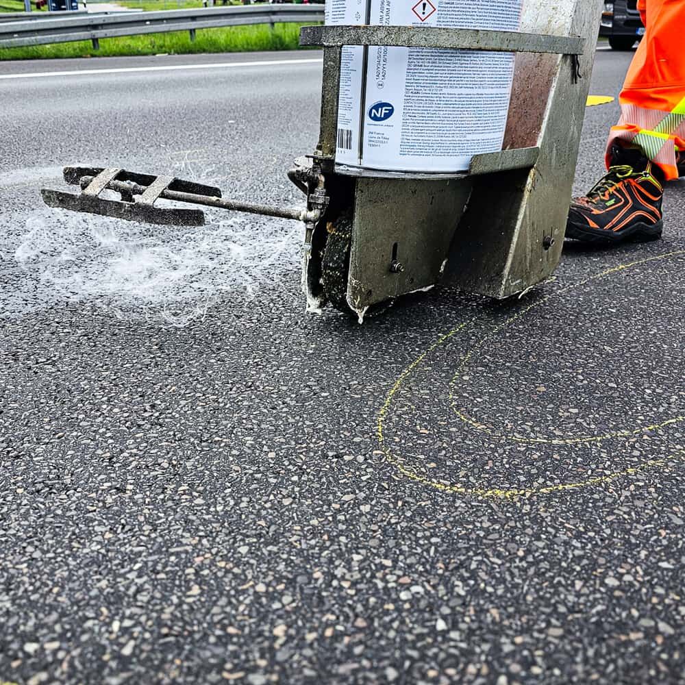 Detailaufnahme: 3M PS-98 Grundierungsgerät trägt Primer auf Fahrbahnoberfläche auf