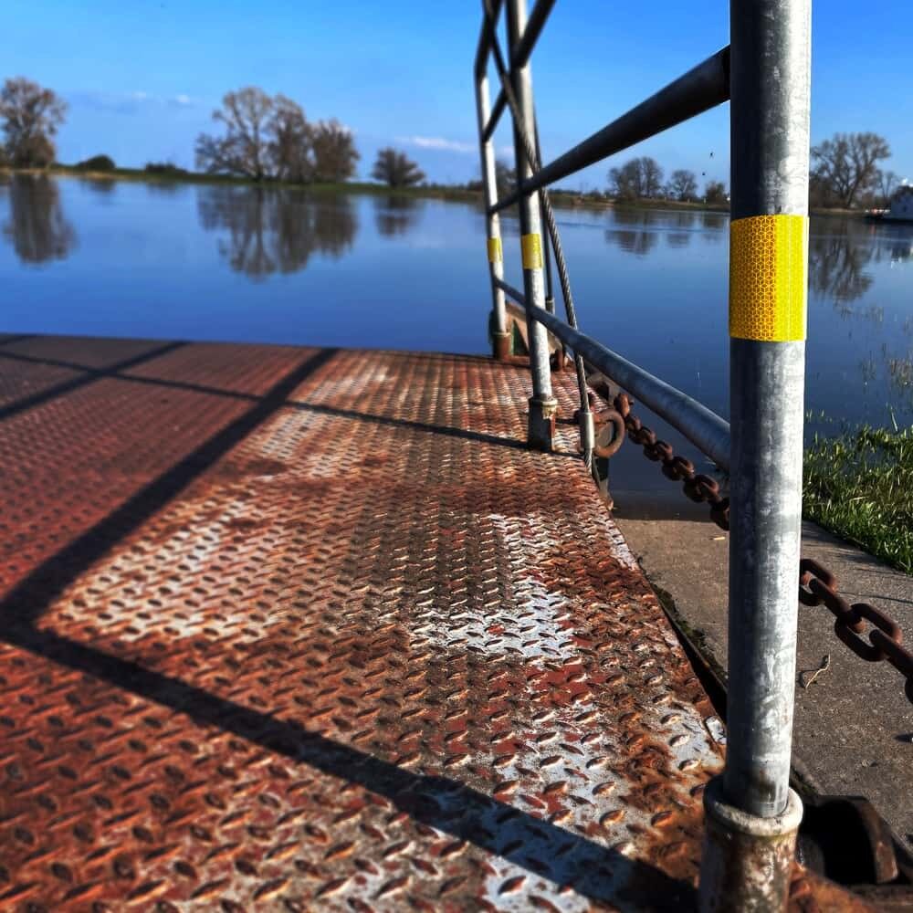 Gelbes Orafol VC 170 Reflexband markiert Metallgeländer an Bootssteg über Wasser bei Tag.