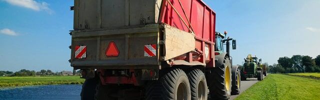 Heckwarnmarkierungen nach ECE 69 Ein landwirtschaftlicher Anhänger mit rot-weißen Warntafeln und Heckwarntafel nach ECE 69 an der Rückseite, gezogen von einem Traktor.