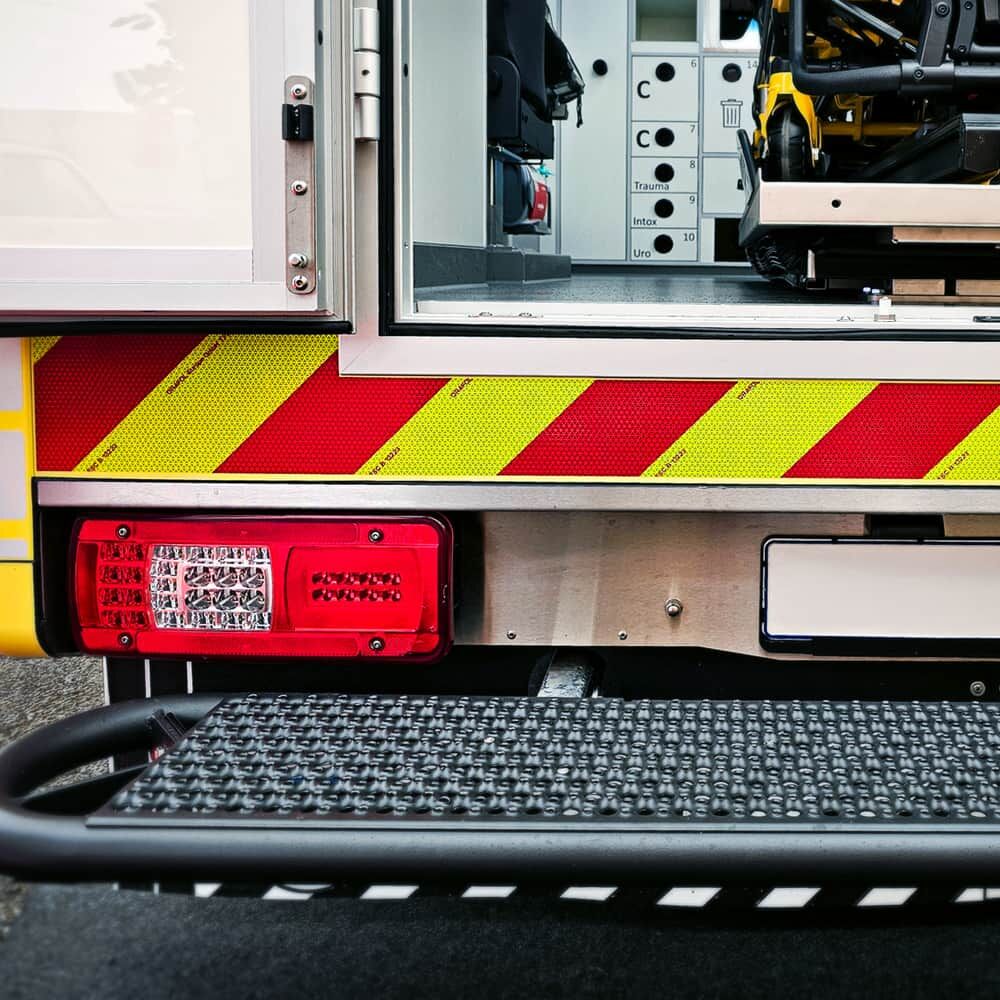 Hecktritt Ambulanzfahrzeug mit ORALITE VC 612 Fluorlime-Rot-Band und Rückleuchte.