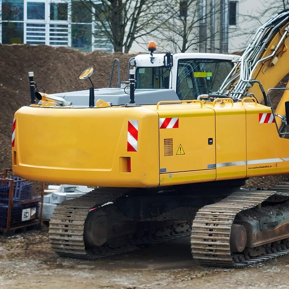 Gelber Bagger mit aufgeklebten Orafol 5921M Warnmarkierungs-Zuschnitten
