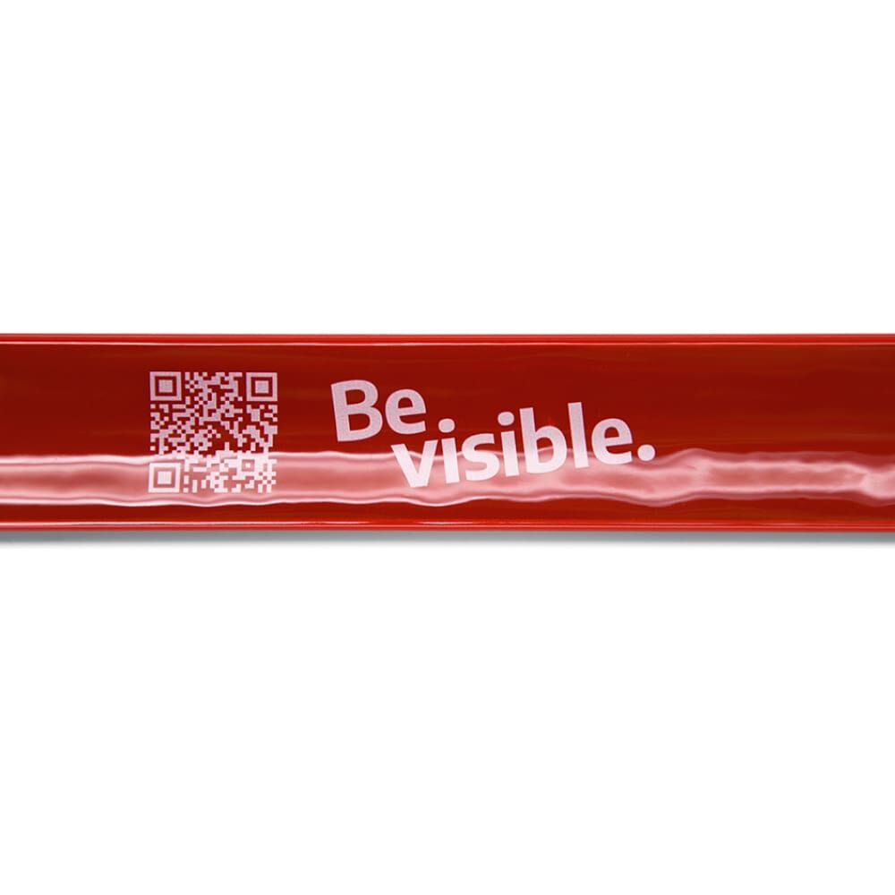 Detail: reflektierende Oberfläche des roten Bands, weißer „Be visible.“-Aufdruck neben QR Code