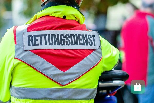 Eine neongelbe Rettungsdienst-Weste mit reflektierendem „RETTUNGSDIENST“-Schriftzug, roten Elementen und silbernen Reflexstreifen.