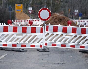  Straßensperre mit rot-weißen Absperrschranken und einem runden Durchfahrtsverbotsschild.