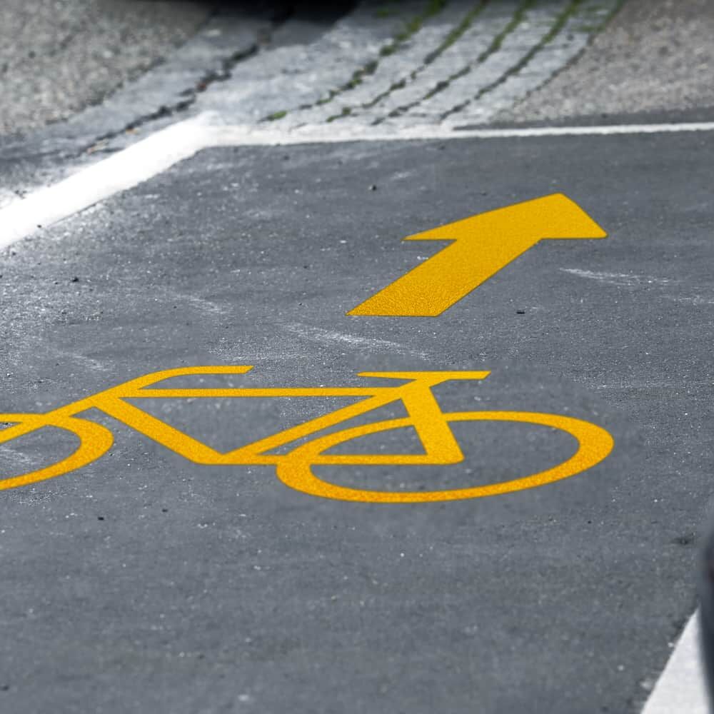 3M Stamark Fahrrad-Symbol in Gelb mit Richtungspfeil auf Radweg appliziert