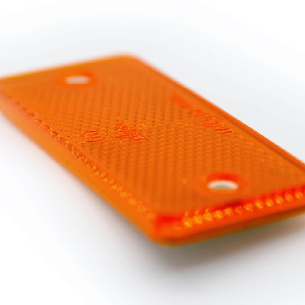 Detailansicht: rechteckiger oranger Reflektor 90×40 mm, zwei Befestigungslöcher