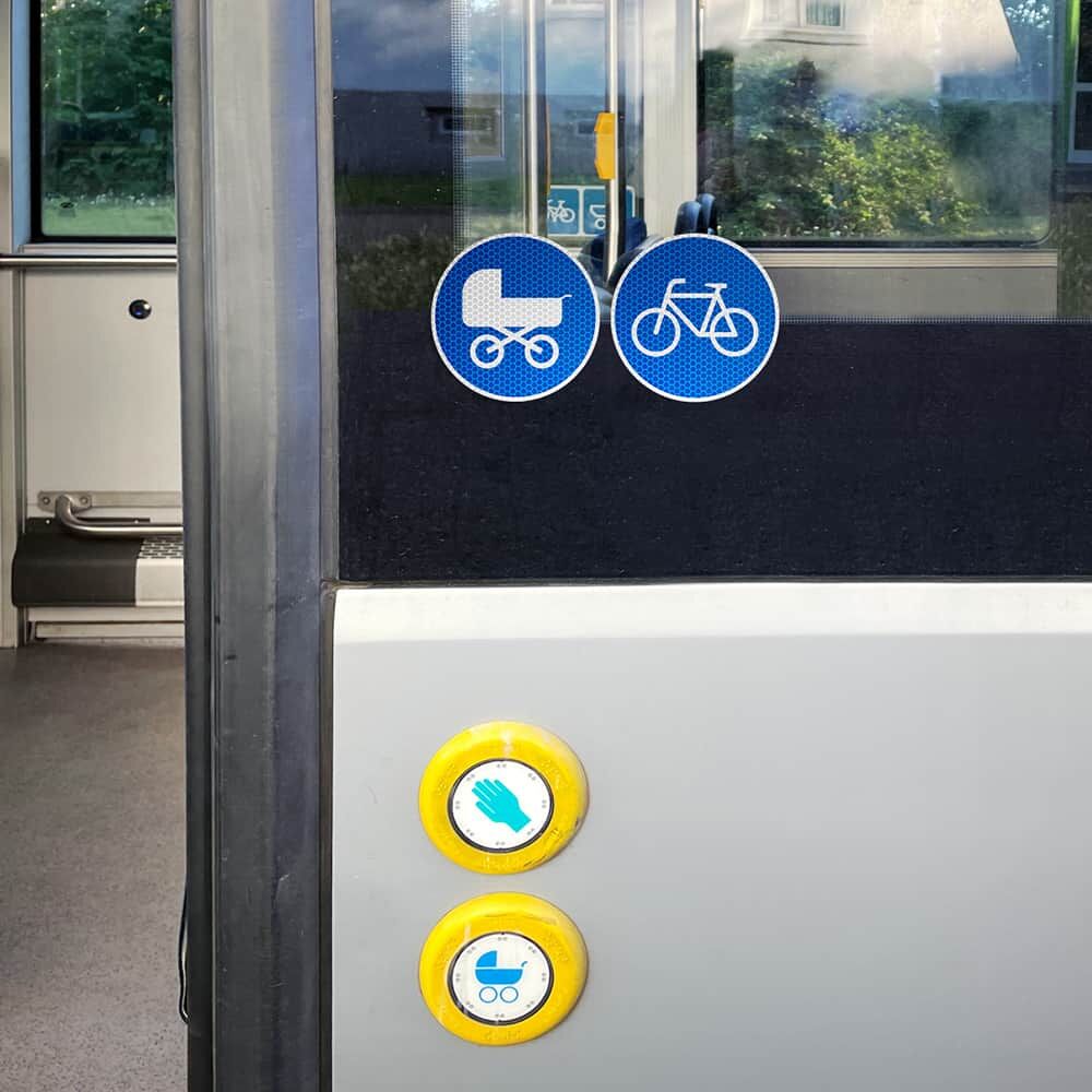 Radweg-Aufkleber an Bustür neben Kinderwagen-Symbol, Anwendung im öffentlichen Verkehr
