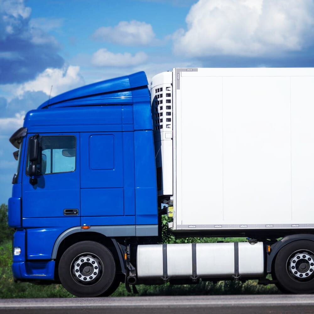 Blauer Lkw mit weißem Koffer, seitlich markiert mit gelbem VC104+RG Logostreifen