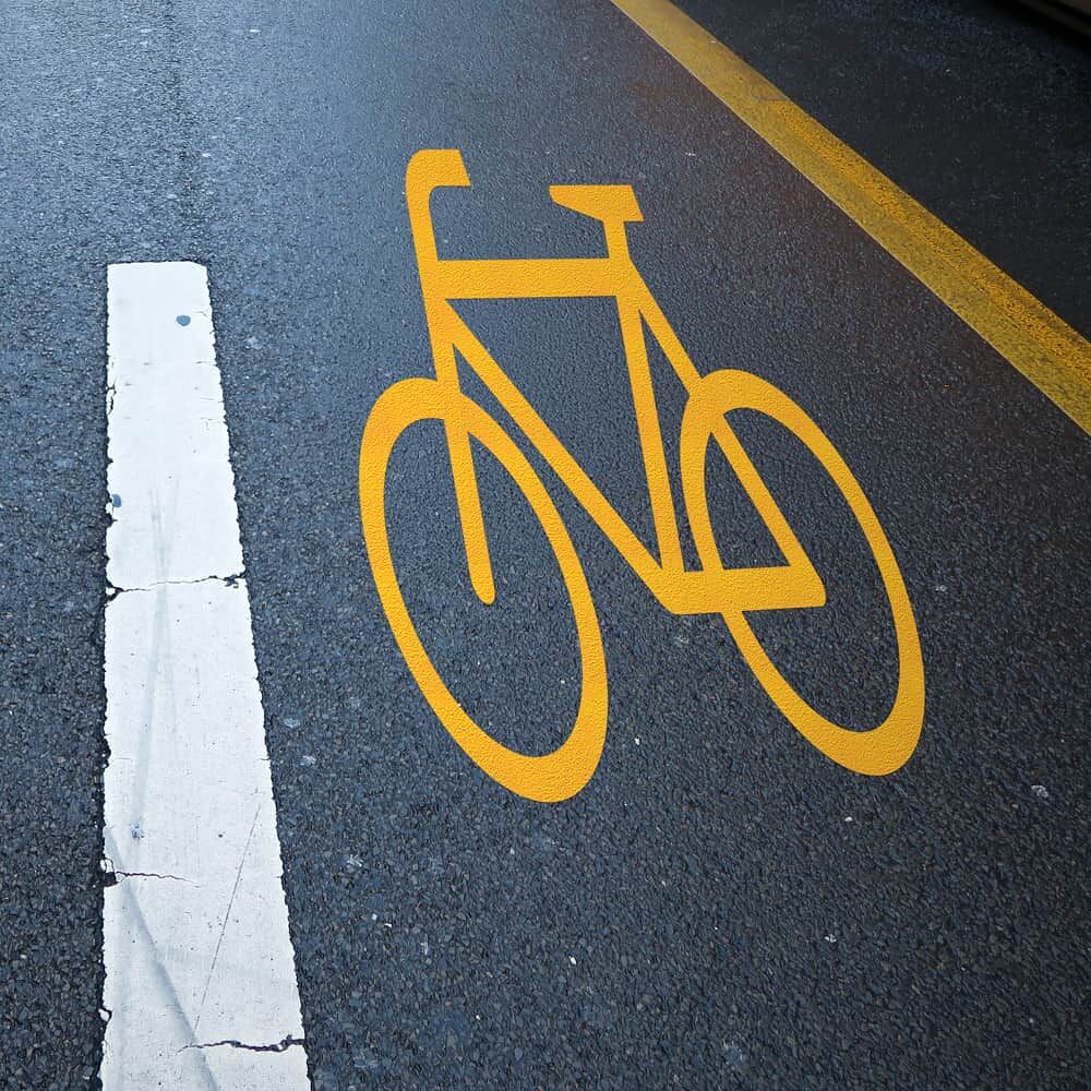 Fahrbahnmarkierung mit gelbem Fahrrad-Piktogramm aus 3M Stamark auf dunklem Asphaltbelag