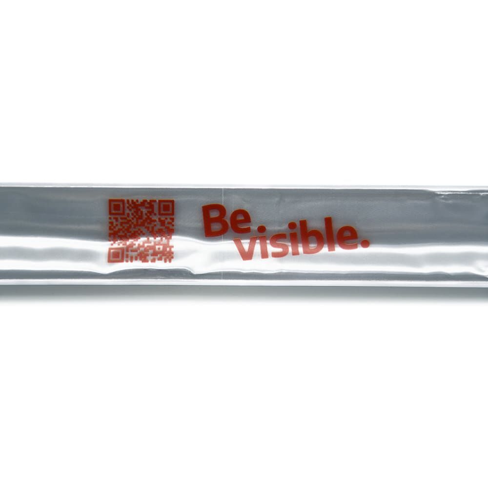 Detail: reflektierende Oberfläche des weißen Bands, roter „Be visible.“-Aufdruck neben QR Code