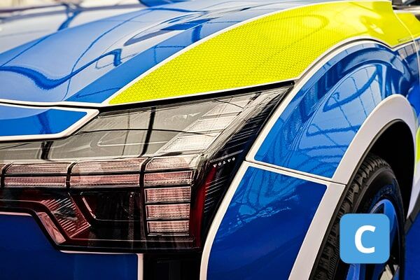 Nahaufnahme eines modernen LED-Scheinwerfers eines Polizeiautos mit blau-gelber Lackierung.