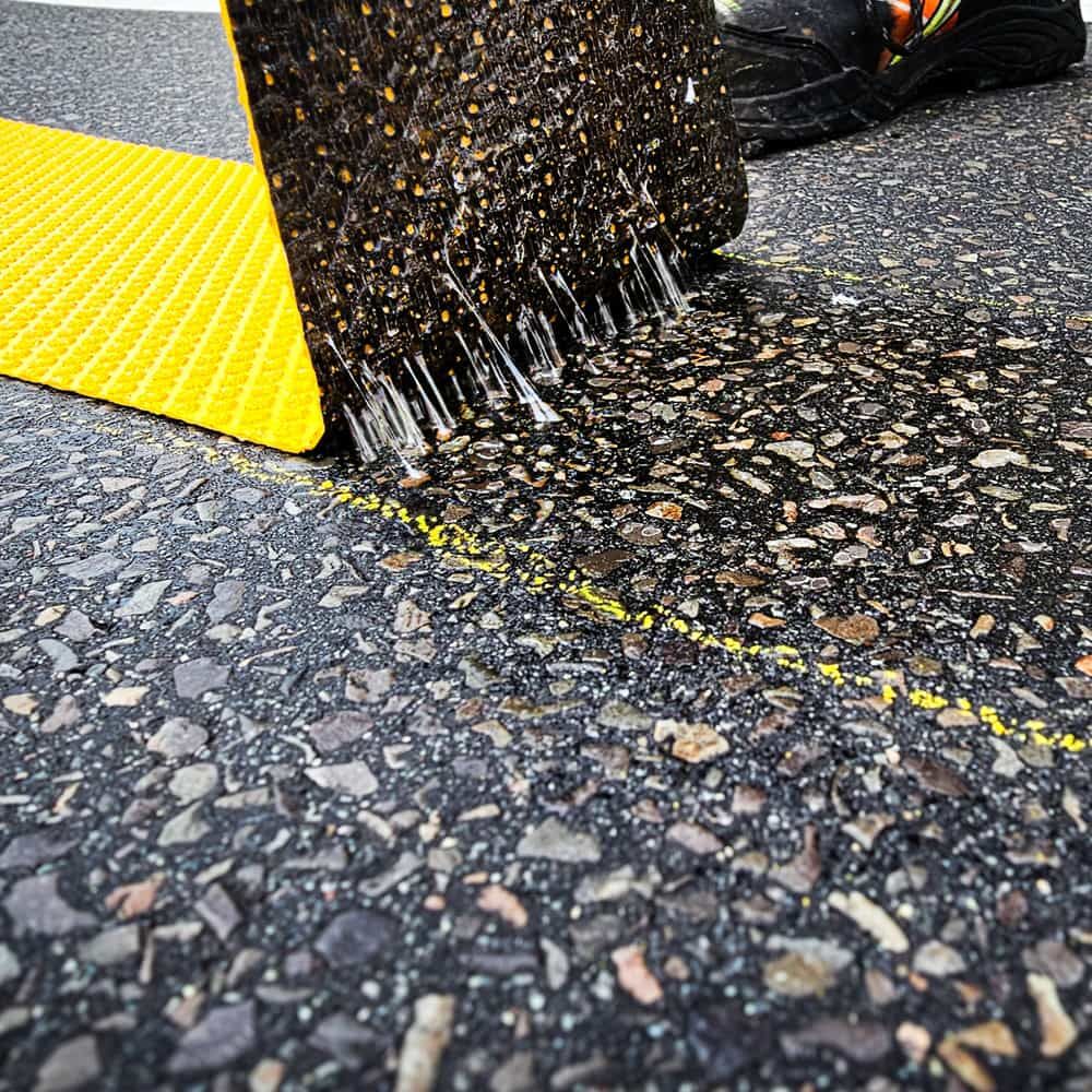 Rückseite der 3M Stamark Fahrbahnmarkierung, mit Klebstoffspikes beim Abziehen vom Asphalt sichtbar