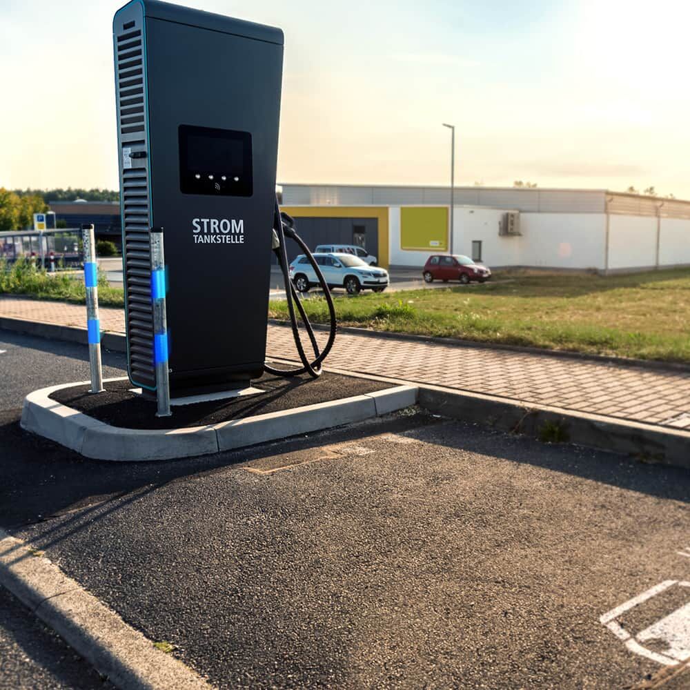 Blau markierte Leitpfosten mit 5810-Reflexband sichern Schnellladestation auf Parkplatz