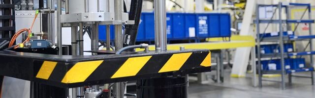Eine Maschine steht in einem Lager, gesichert durch schwarz-gelbe Industriemarkierung.