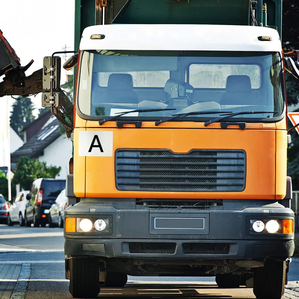 A-Schild-Aufkleber auf Front eines orangefarbenen Entsorgungs-Lkw im Einsatz
