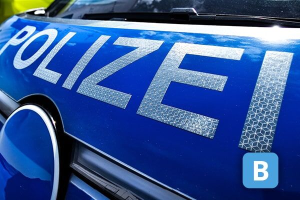 Nahaufnahme des reflektierenden „POLIZEI“-Schriftzugs auf einem blauen Polizeifahrzeug.