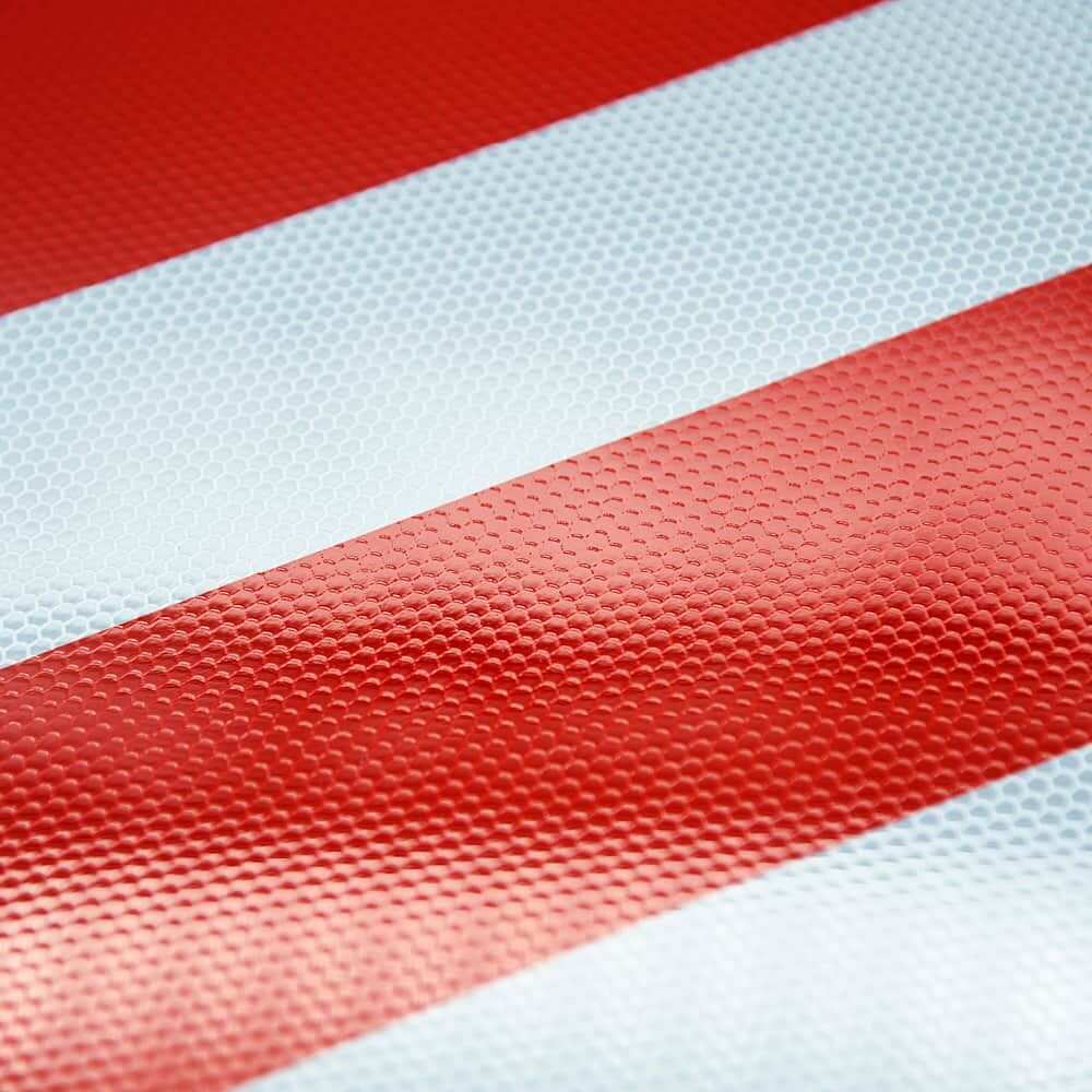 Detail: reflektierende Oberfläche mit rot/weißen Diagonalstreifen (Nahaufnahme)