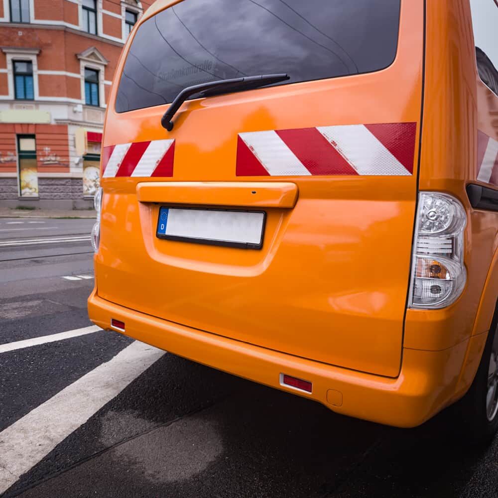 Orange Kleintransporter hinten mit 3M 3410 Warnmarkierungsstreifen linksweisend