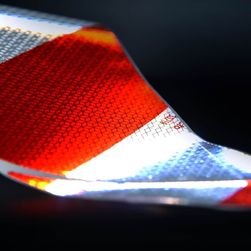 Reflektierende Folie im Licht mit rot-silbernem Muster und Mikroprismenstruktur