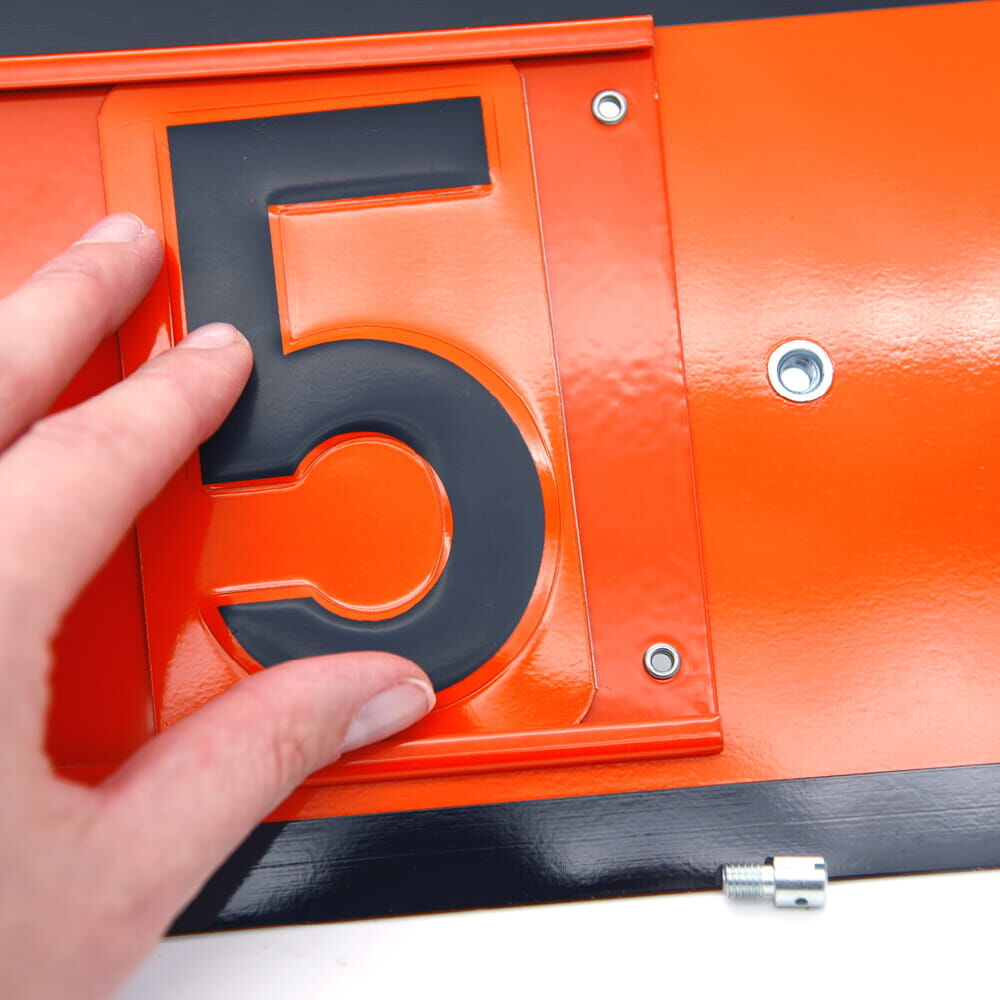 Hand setzt schwarze Ziffer 5 in orange ADR-Tafel ein, Verschraubung unten sichtbar.