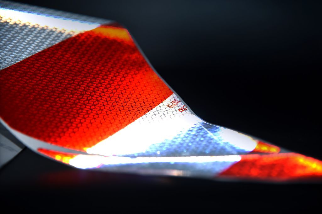 Reflektierende Folie im Licht mit rot-silbernem Muster und Mikroprismenstruktur