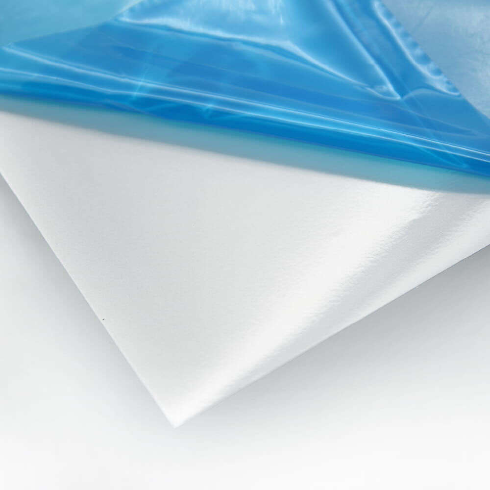 Weißer Transferfilm mit teilweise entfernter blauer Schutzfolie auf glänzendem Liner.