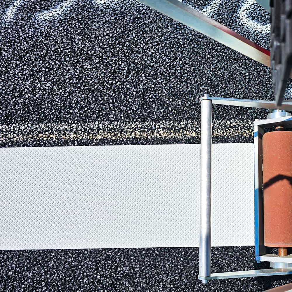 Nahaufnahme: 3M Folienverlegegerät MTA-II trägt Folie auf Asphalt auf