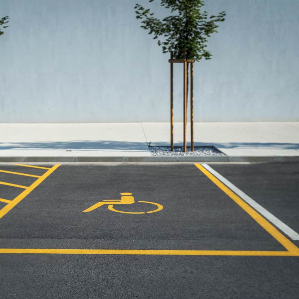 Parkplatzmarkierung Behindertenparkplatz mit gelbem Rollstuhlsymbol auf Asphalt