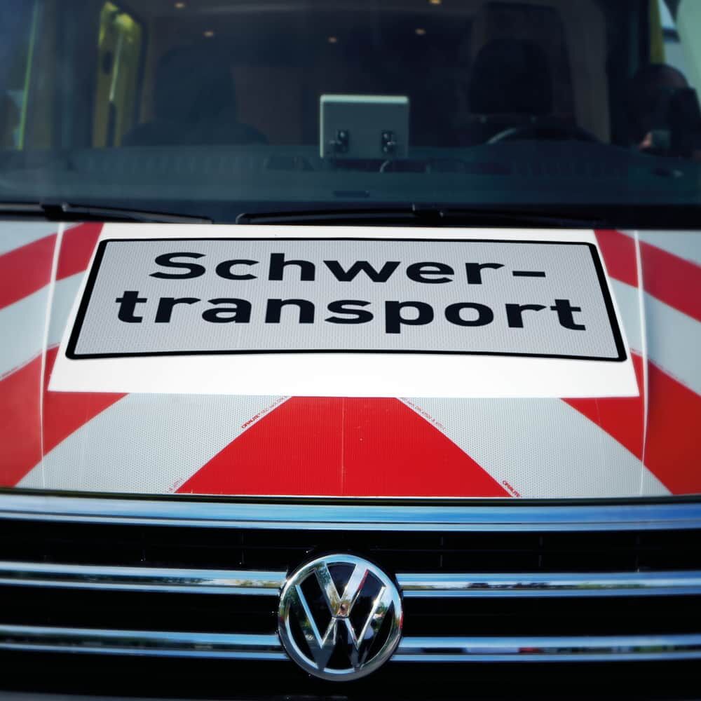 Nahaufnahme Schild „Schwertransport“ auf Motorhaube eines VW-Begleitfahrzeugs