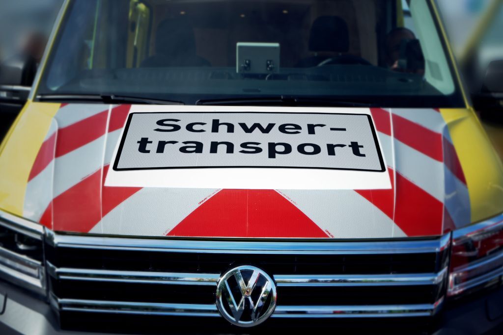Nahaufnahme Schild „Schwertransport“ auf Motorhaube eines VW-Begleitfahrzeugs