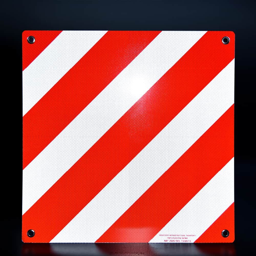 Warntafel für Italien rot-weiß diagonal auf dunklem Hintergrund, starke Reflexion sichtbar