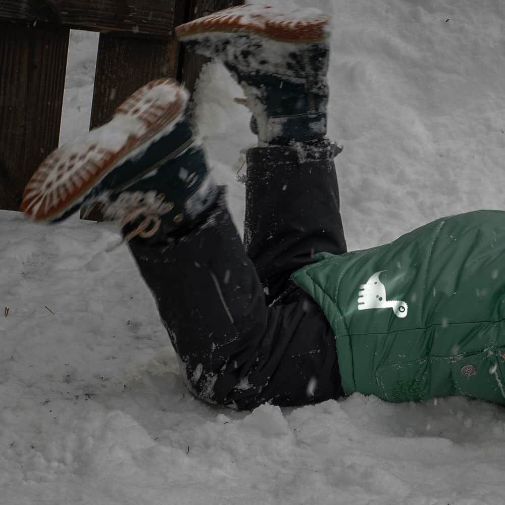 Reflektierender Dino-Bügelprint auf Kinderjacke im Schnee, erhöht Sichtbarkeit in Dunkelheit