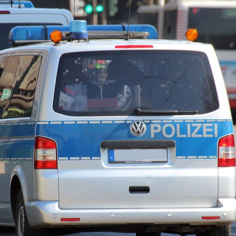 Rückansicht eines silber-blauen Polizeivans mit segmentierter, weißer Konturmarkierung