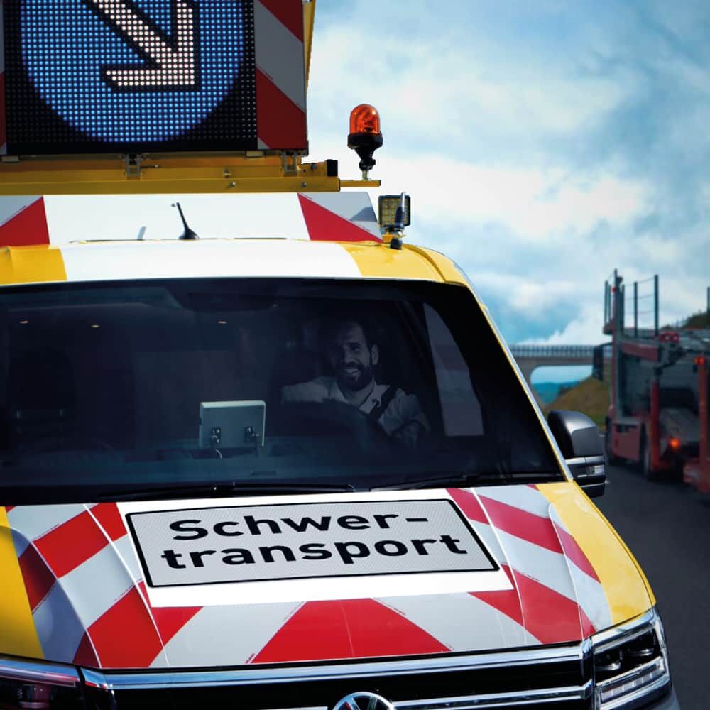 Frontansicht Begleitfahrzeug mit Schild „Schwertransport“ und beleuchtetem Warndisplay