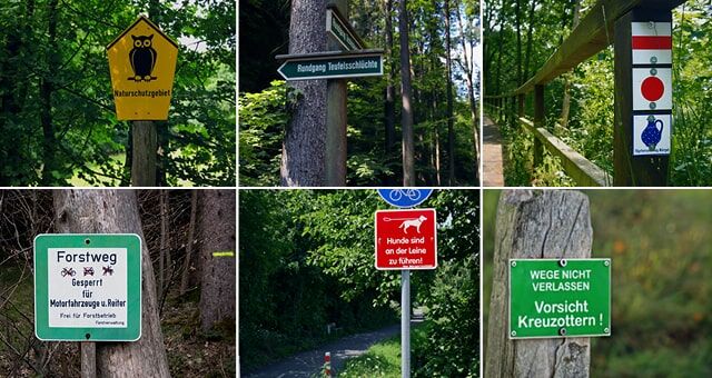 Verschiedene Warn- und Hinweisschilder in einem Waldgebiet
