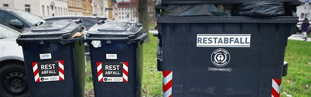 Schwarze Restmülltonnen mit rot-weißen Warnmarkierungen und 'Restabfall' Beschriftung
