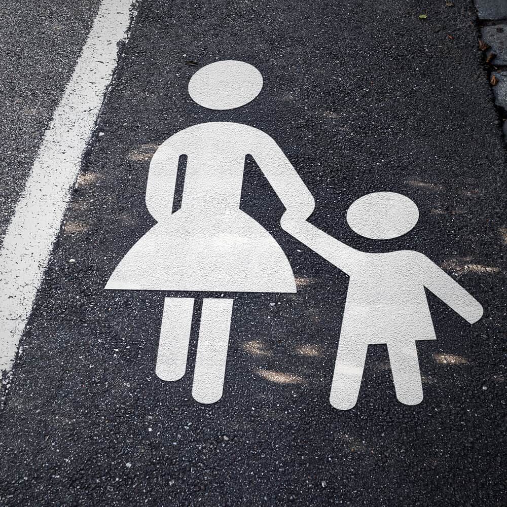 Weißes Mutter-Kind Fahrbahnzeichen frisch auf Asphalt neben Randlinie appliziert