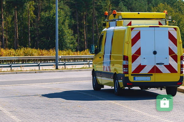 Gelbes Begleitfahrzeug mit rot-weißer Heckwarnmarkierung und Dachbalken.