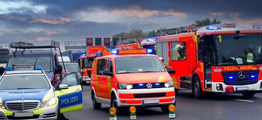 Einsatzfahrzeuge von Polizei, Feuerwehr und Rettungsdienst auf einer Autobahn mit dramatischem Himmel.