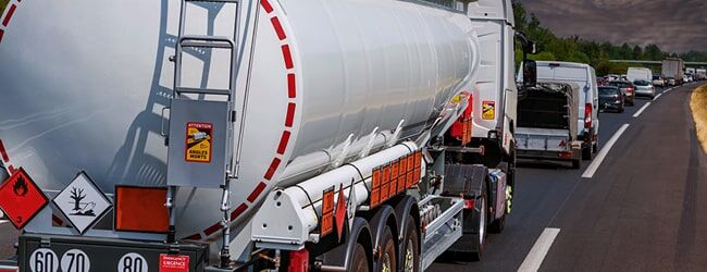 Tankwagen mit Gefahrgutzeichen im Stau auf der Autobahn, rote Warnmarkierungen sichtbar.