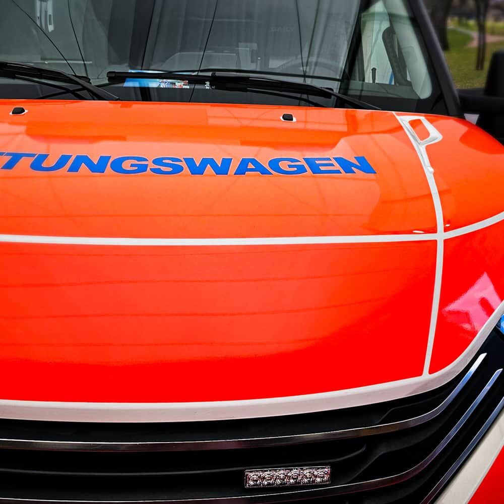 Rettungswagen-Motorhaube mit oranger ORACAL Fluorfolie 7510 Premium und blauer Schrift