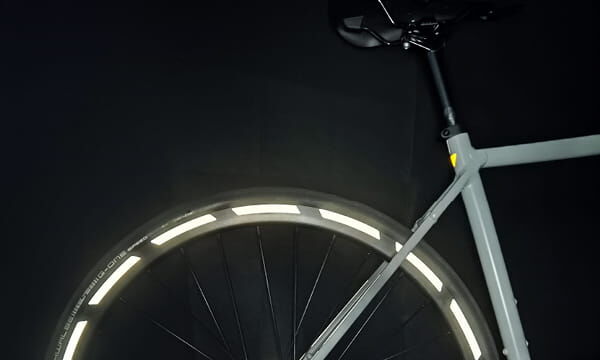 Rennrad mit reflektierenden Felgenstreifen bei Dunkelheit.