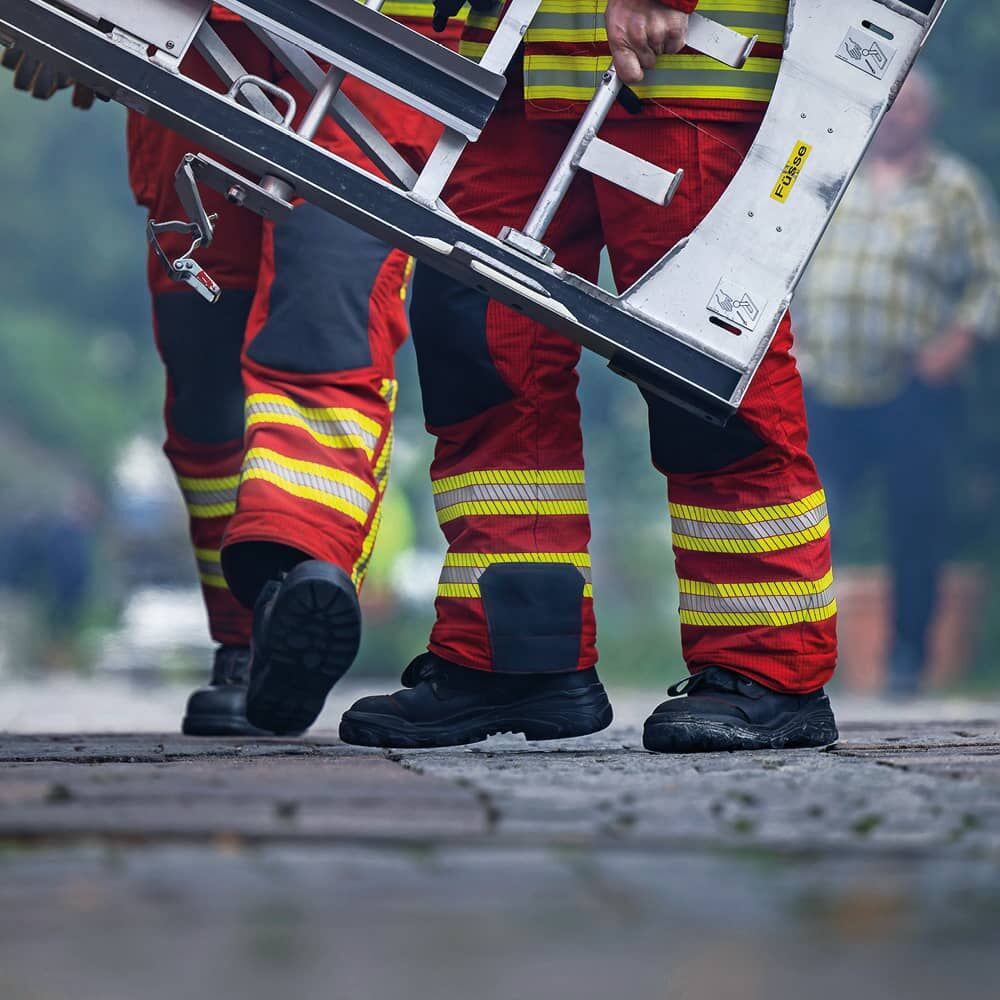 Feuerwehrkräfte tragen rote Einsatzkleidung mit gelb-silber-gelb 3M Scotchlite 5697 Reflexstreifen